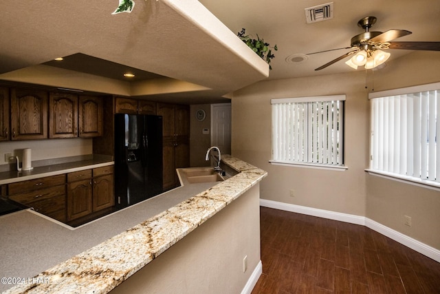 kitchen with dark wood-type flooring, sink, black fridge, dark brown cabinets, and ceiling fan