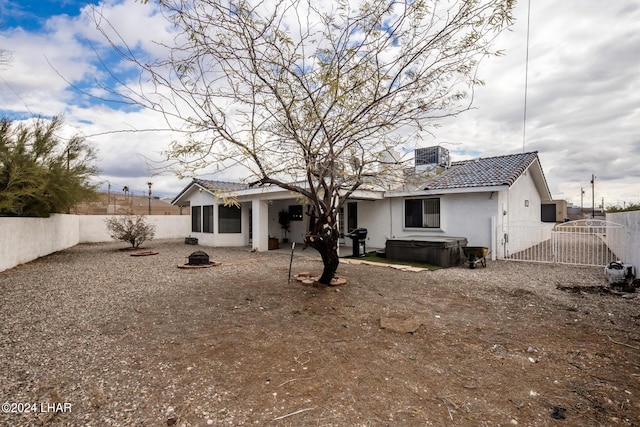 back of house with a hot tub and central air condition unit