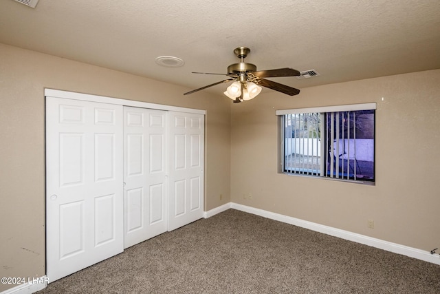 unfurnished bedroom with ceiling fan, carpet, a textured ceiling, and a closet