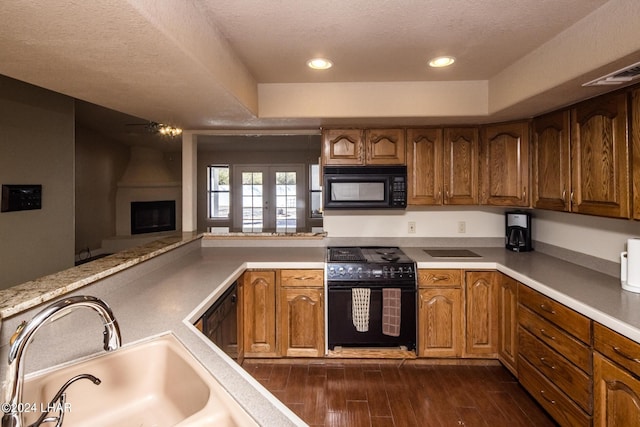 kitchen with french doors, sink, a large fireplace, dark hardwood / wood-style floors, and black appliances