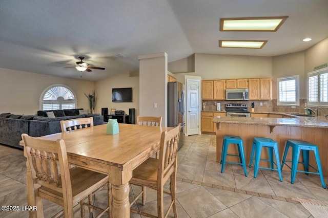 dining space featuring lofted ceiling, light tile patterned floors, and a ceiling fan