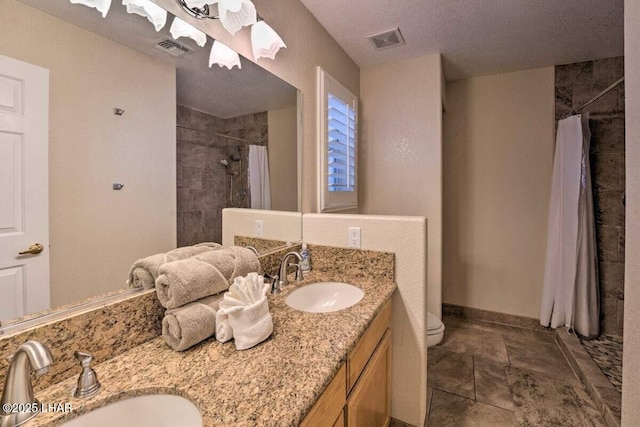 bathroom with visible vents, a tile shower, and a sink