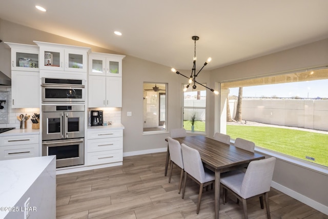 2008 Martinique Dr, Lake Havasu City, AZ 86406 - kitchen with backsplash, stainless steel double oven, white cabinetry, a chandelier, and lofted ceiling