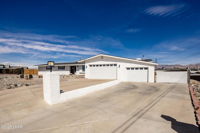 single story home featuring driveway, a garage, fence, and stucco siding