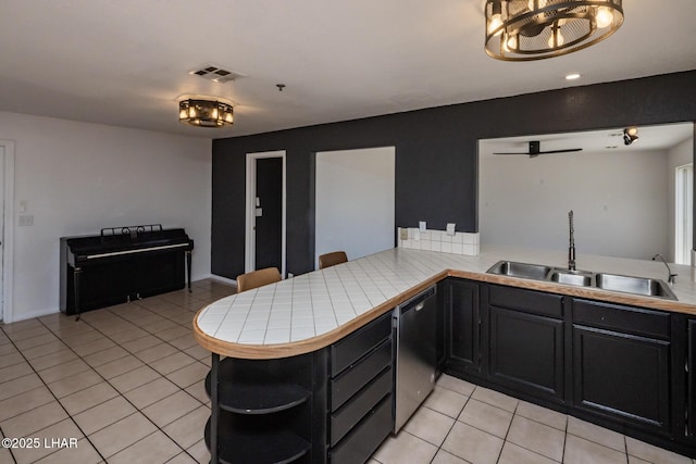 2230 Havasupai Blvd, Lake Havasu City, AZ 86403 - kitchen featuring stainless steel dishwasher, a sink, light tile patterned floors, tile countertops, and open shelves