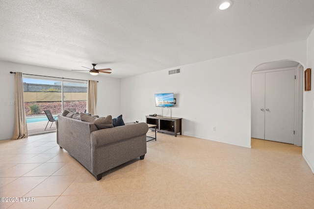 living room with arched walkways, ceiling fan, a textured ceiling, and visible vents