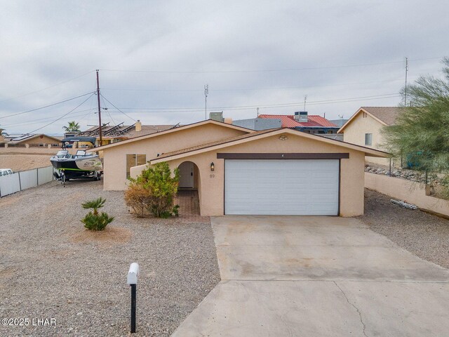 ranch-style house featuring a garage, concrete driveway, fence, and stucco siding