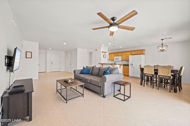 living area featuring recessed lighting, visible vents, ceiling fan with notable chandelier, and light tile patterned flooring