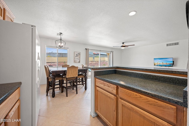 kitchen featuring white fridge with ice dispenser, dark countertops, visible vents, and light tile patterned floors