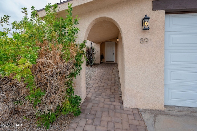 property entrance with an attached garage and stucco siding