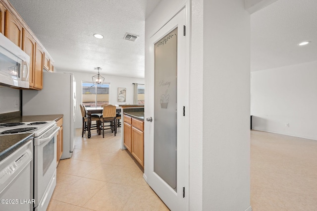 kitchen with decorative light fixtures, dark countertops, visible vents, a textured ceiling, and white appliances