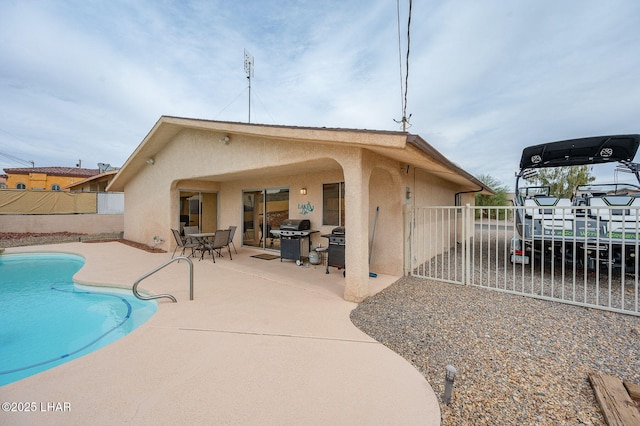 rear view of property with a fenced in pool, a patio, fence, and stucco siding