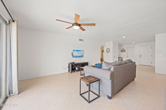 living area with light tile patterned floors, visible vents, arched walkways, ceiling fan, and recessed lighting