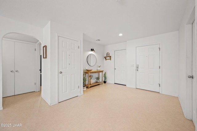 foyer with light floors, arched walkways, and recessed lighting