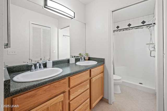 full bath featuring double vanity, tile patterned floors, a sink, and a shower stall