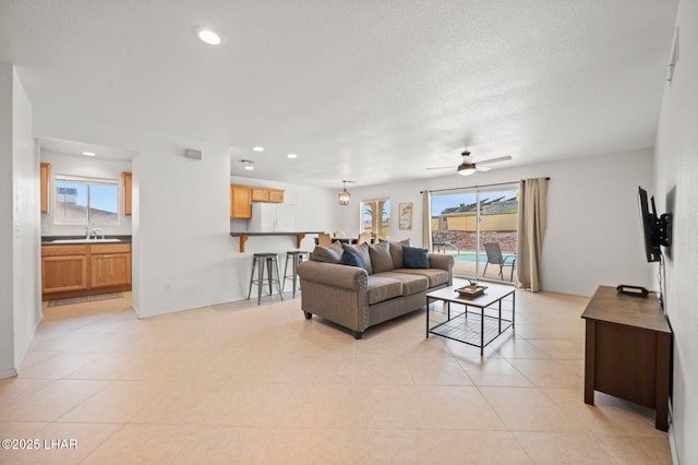 living room featuring a textured ceiling, ceiling fan, light tile patterned floors, and recessed lighting