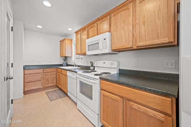 kitchen featuring white appliances, light tile patterned floors, dark countertops, a sink, and recessed lighting