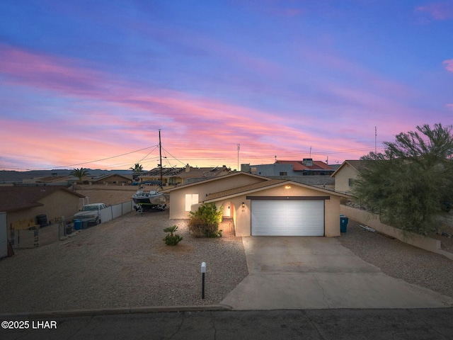 view of front of house featuring a garage, fence, concrete driveway, and stucco siding