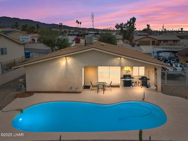 pool at dusk with fence private yard, a patio area, a grill, and cooling unit