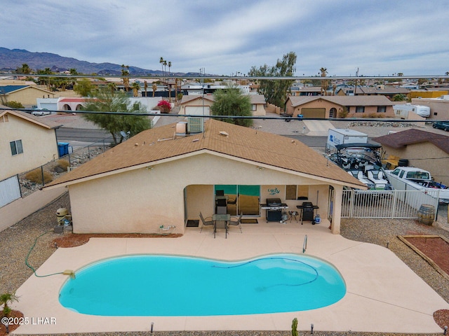 pool featuring a patio, a grill, a mountain view, a residential view, and a fenced backyard