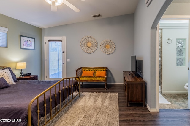 bedroom with arched walkways, dark wood-style flooring, visible vents, and baseboards