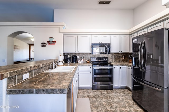 kitchen featuring visible vents, appliances with stainless steel finishes, a peninsula, white cabinetry, and a sink