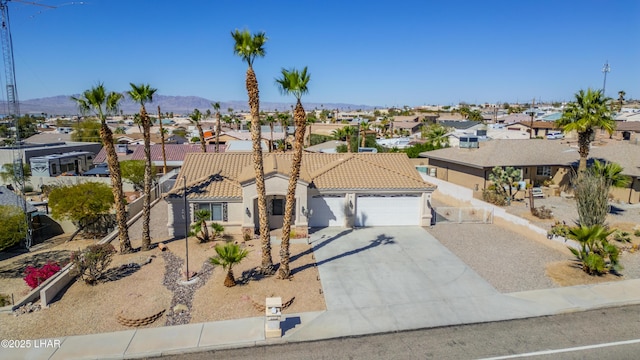 mediterranean / spanish home with an attached garage, driveway, a tile roof, and a residential view