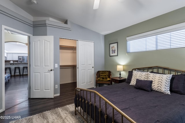 bedroom featuring arched walkways, lofted ceiling, refrigerator, a closet, and dark wood-style floors