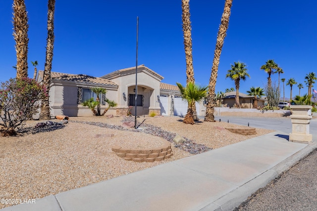 mediterranean / spanish house with a garage, a tile roof, and stucco siding