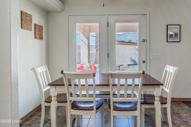 dining room featuring dark tile patterned flooring and baseboards