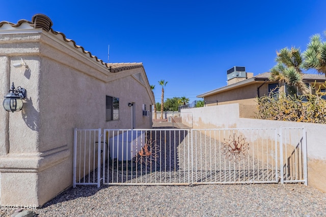 view of side of home with central air condition unit, fence, a tiled roof, and stucco siding