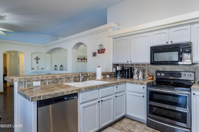 kitchen with stainless steel appliances, white cabinetry, a sink, and a peninsula