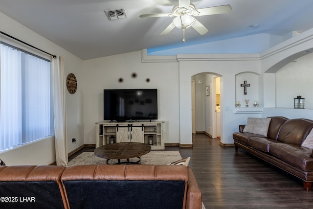 living area featuring arched walkways, lofted ceiling, wood finished floors, visible vents, and plenty of natural light