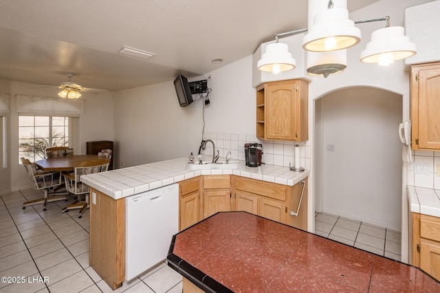 kitchen with arched walkways, backsplash, a sink, dishwasher, and a peninsula