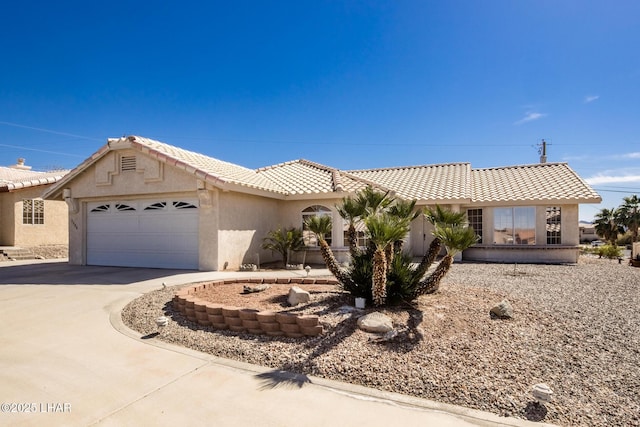 view of front of property featuring driveway, a tiled roof, an attached garage, and stucco siding