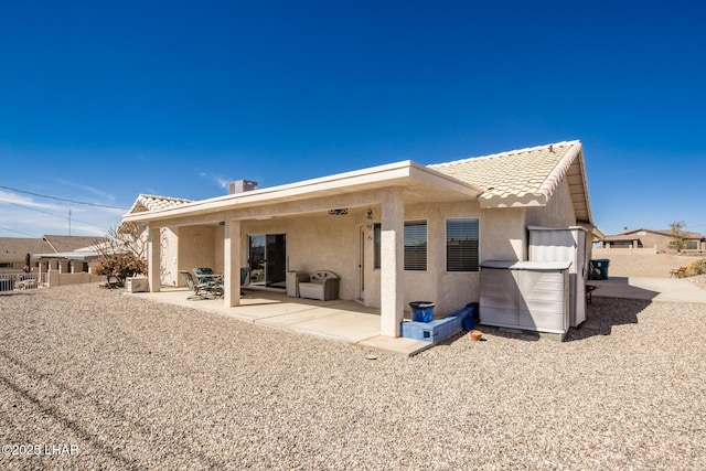 rear view of property with a tiled roof, a patio area, and stucco siding