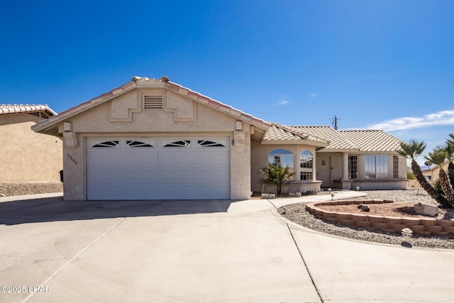 view of front of house with driveway, an attached garage, a tile roof, and stucco siding