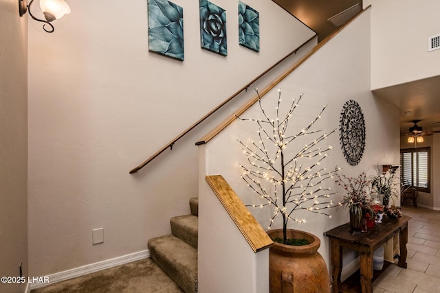 staircase with visible vents, a ceiling fan, and baseboards