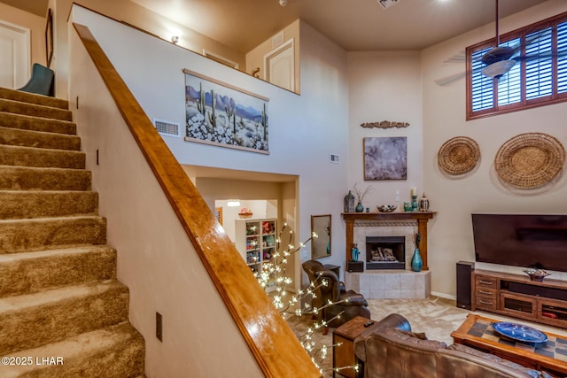 staircase with a tiled fireplace, a high ceiling, and visible vents