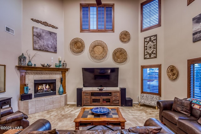 carpeted living room with visible vents, a fireplace, a high ceiling, and baseboards