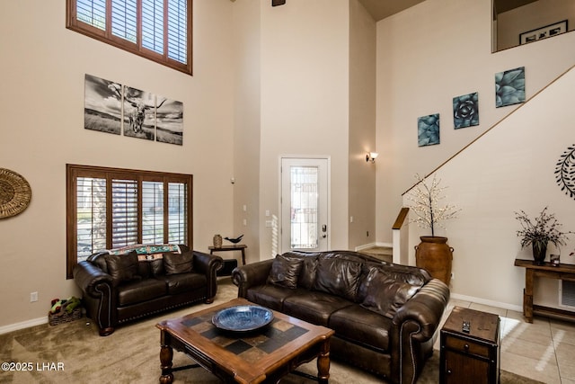 living area with baseboards, light carpet, and a high ceiling