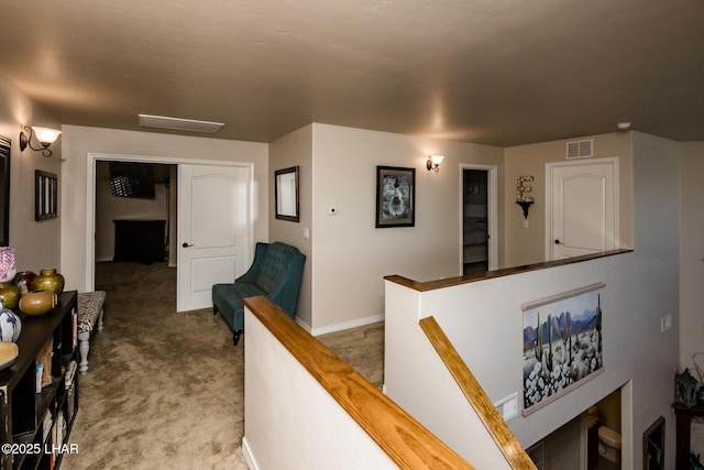 hallway featuring an upstairs landing, visible vents, and carpet