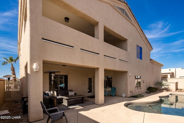 rear view of house with stucco siding, fence, and a patio area