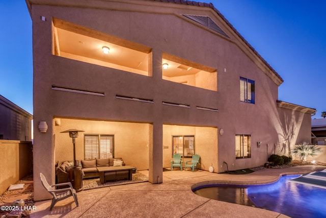 back of house featuring stucco siding, visible vents, an outdoor living space, a fenced in pool, and a patio area