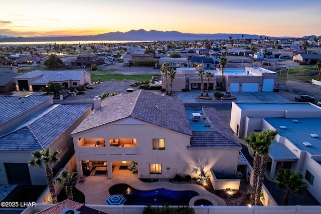 aerial view at dusk featuring a mountain view and a residential view