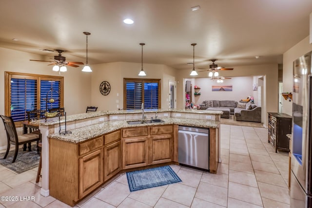 kitchen with a ceiling fan, a sink, open floor plan, appliances with stainless steel finishes, and light tile patterned flooring