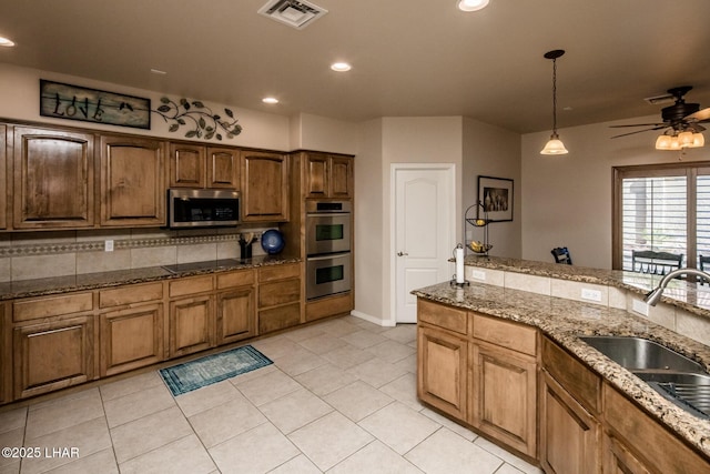 kitchen featuring visible vents, a sink, appliances with stainless steel finishes, decorative light fixtures, and tasteful backsplash