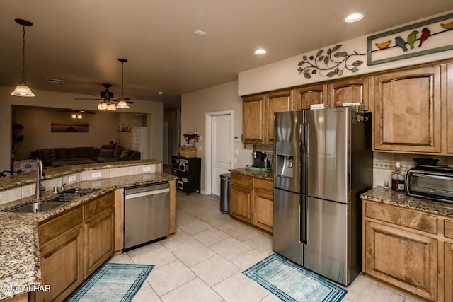 kitchen featuring hanging light fixtures, stone counters, appliances with stainless steel finishes, and a sink