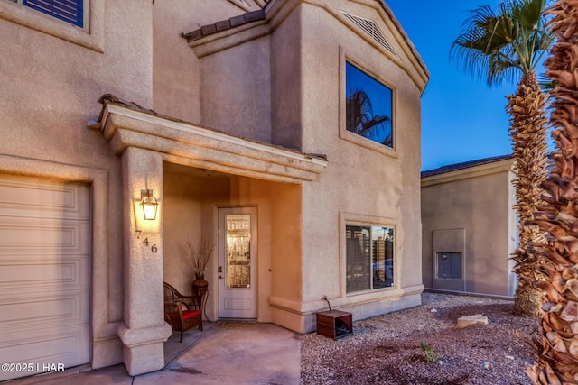 entrance to property featuring visible vents and stucco siding