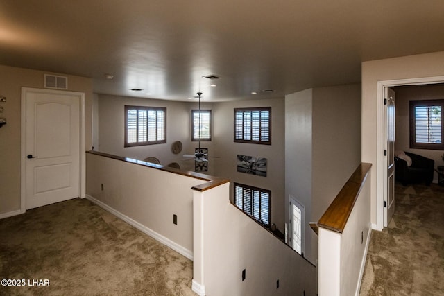 hallway featuring baseboards, visible vents, an upstairs landing, and carpet floors